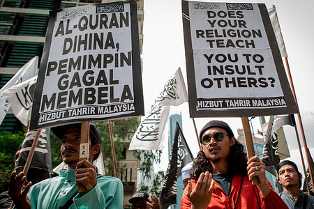 Two men from a Malaysian Islamist group hold placards while praying during a peaceful march and rally in front of the Dutch embassy protesting the desecration of a Quran by a Dutch political leader in Kuala Lumpur. They were protesting against Edwin Wagensveld, head of the Dutch chapter of the German Patriotic Europeans Against the Islamization of the Occident, abbreviated as Pegida, who tore pages from the Islamic holy book and stepped all over them at The Hague earlier this week.