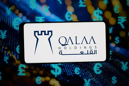 In this photo illustration, the logo of investment company Qalaa Holdings S.A.E. is displayed on a smartphone in front of abstract background on computer screen.