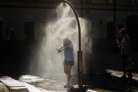 A young girl enjoys the relief of a cooling misting station. On the afternoon of the 28th of June, Varsovians cool and hydrate themselves around the city during a record-breaking heatwave. Due to the extreme heat, the authorities provided misting sprays and water tanks around the city. During the weekend, Warsaw experienced temperatures approaching 38°C as the unprecedented European heatwave swept across Poland, roughly 15°C above the late-June average. Tropical nights, nationwide heat alerts, and temperatures up to 40.5°C elsewhere in the country made this one of the most extreme heat events in modern Polish history.