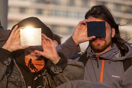 People watch the solar eclipse on the shore of the Gulf of Finland