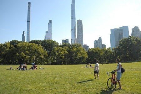 A person holds a bicycle in Sheep Meadow lawn in Central Park, Manhattan, New York City.