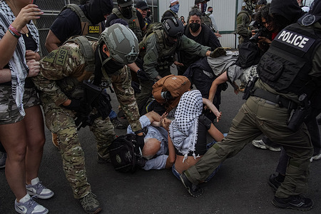 Federal Agents scuffle with protestors, pushing them to the ground, outside Delaney Hall Detention Facility during a demonstration. Demonstrators gathered outside of the facility, where four detainees escaped after allegedly breaking through a wall, to voice opposition to increased raids against migrants.