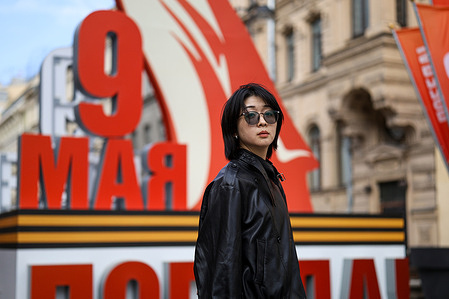 A woman walks against the backdrop of a large red festive installation "May 9", decorated with a St. George's ribbon, on Bolshaya Morskaya Street in St. Petersburg.