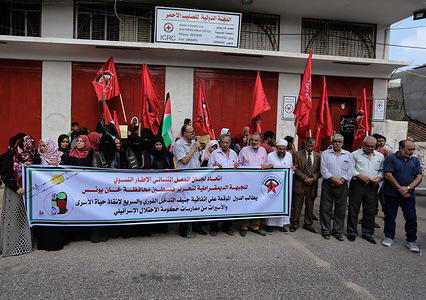 Palestinians hold a banner and flags in front of the Red Cross headquarters during the protest demanding the release of Palestinian prisoners from Israeli jails in southern Gaza.