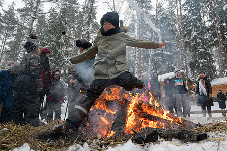 A boy jumps over a bonfire left after the burning of an effigy during celebrations of Maslenitsa (Shrovetide), a traditional Russian folk festival marking the end of winter, at Emerald Lake in the village of Toksovo in the Leningrad region.