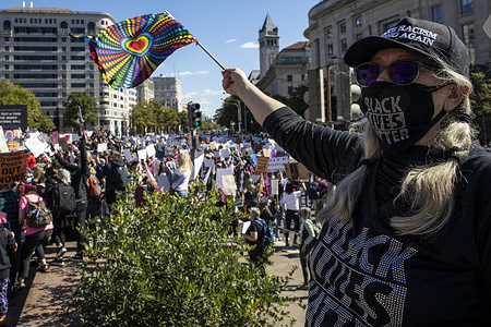 A woman wearing Black Lives Matter mask waves a rainbow flag during the demonstration.
Women's March, a feminist organization, planned a rally and marched to bring opposition against President Donald Trump, and his plans to fill the Supreme Court seat left by Ruth Bader Ginsburg with Amy Coney Barrett. Barrett's conservative politics leave many believing she may overturn Roe Wade's decision on abortion rights and may also overturn LGBTQ rights decisions as well. Along with that agenda many participants in the march stood up for Black Lives Matter and voting rights for Puerto Rico and the District of Columbia. The march started in Freedom Plaza with a rally and speakers, then marched to the Supreme Court, where speakers continued to talk and was supposed to end on the National Mall. The whole event lasted from 11am to 5pm, and was waylaid by a counter protest by Students for Life, an anti-abortion group, in front of the Supreme Court.