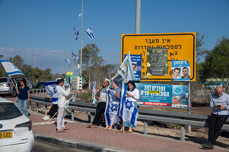 Citizens with Israeli flags wait as a sign of solidarity along the road where the convoy of vehicles including the hostages who were released from captivity in Gaza and held by Hamas for two years is scheduled to pass.