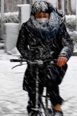 A man rides a bicycle in the falling snow in central Tokyo.
