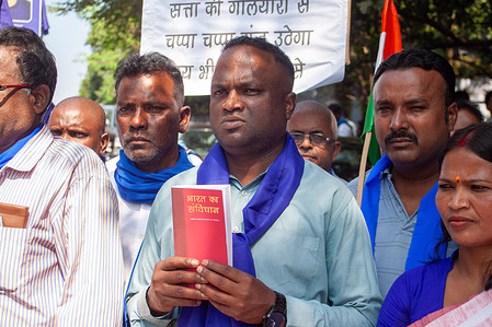 A protester holds a copy of the Constitution of India during a demonstration. Protesters gathered to condemn senior advocate Rakesh Kishore, who threw a shoe at Chief Justice of India B.R. Gavai during a Supreme Court session in New Delhi. Kishore shouted religious slogans in protest against the CJI’s remarks on a religious issue. The demonstrators called for justice, equality, and respect for constitutional values over acts of hate and discrimination.
