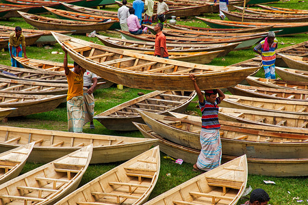 Craftsmen seen carrying a boat among hundreds of little wooden boats displayed for sale at a market as locals prepare for monsoon season. 
Dozens flock from miles around to buy their own boat at a market in Manikganj, Bangladesh, so as to be prepared for floods which can strike at any time. After heavy rainfall it is common for river banks to burst, submerging nearby towns and villages. This means cars and buses become redundant and people are forced to travel by boat. Each of the wooden boats and oars are hand-made by local craftsmen and can be bought for as little as 1700 Bangladeshi Taka - the equivalent of 20 US dollar.