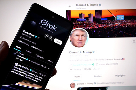 In this photo illustration, Elon Musk's X Profile is seen displayed on a smartphone with the X page of American President Donald Trump in the background.