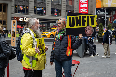 A protester holds "UNFIT" sign during a small anti-war protest organized by Rise and Resists in Times Square on March 22, 2026 in New York City.