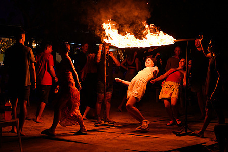 Tourists enjoying a fire limbo activity on Loh Dalum Beach, Phi Phi Island, Thailand.