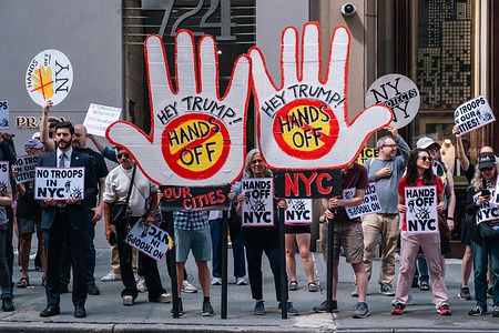 Protesters gather across the street from Trump Tower holding signs that read "Hey Trump! Hands Off" and "No Troops in NYC". Protesters gather outside Trump Tower in Midtown Manhattan to say No to Trump sending Federal Troops.