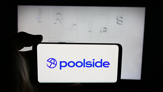 In this photo illustration, a cellphone with the logo of US company Poolside Inc. (Poolside.ai) is seen on screen in front of webpage.