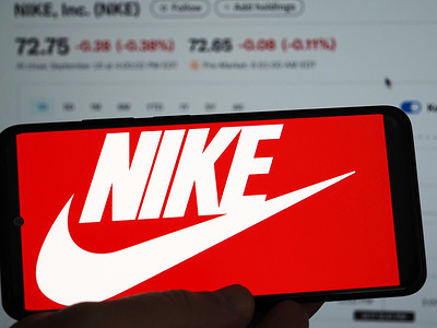 In this photo illustration, the Nike logo is displayed on a smartphone screen with a computer screen in the background.