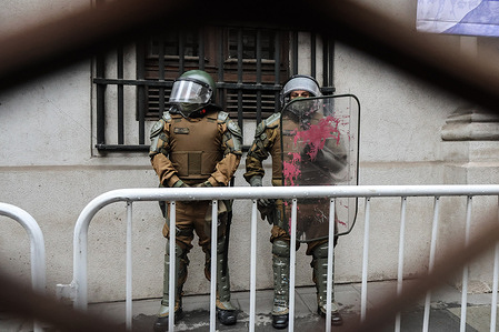 Two police officers protect the Moneda Palace during the march commemorating the 52nd anniversary of the 1973 military coup, an annual event in memory of the thousands of victims of Augusto Pinochet Ugarte's dictatorship.
