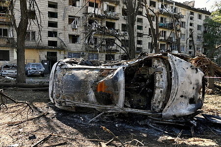 A burnt-out car near a damaged residential building as a result of a missile strike. Following a devastating overnight bombardment in which Russia launched 74 missiles and 496 attack drones, Kyiv has declared July 3, 2026, a city-wide Day of Mourning to honor the victims. At least 25 people were killed and over 80 injured across the capital as direct strikes heavily damaged residential apartment blocks, leaving active search and rescue operations scrambling to locate residents still believed to be trapped under the rubble.