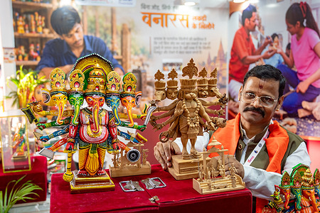 An artist from Varanasi displays traditional wooden artworks, including Panchmukhi Hanuman and Panchmukhi Ganesha statues made from carved wood, representing a centuries-old traditional craft. The fourth Uttar Pradesh International Trade Show (UPITS) takes place from September 25 to 29, 2026, jointly organized by the Government of Uttar Pradesh and India Exposition Mart Limited. The expo showcases the state’s industrial and cultural offerings across 27 manufacturing sectors. With Japan, Russia, and Singapore among the partner nations, the event aims to support export growth by connecting local MSMEs and artisans with international trade delegations.