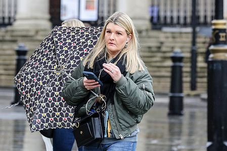 A woman holds her mobile phone while walking in central London.