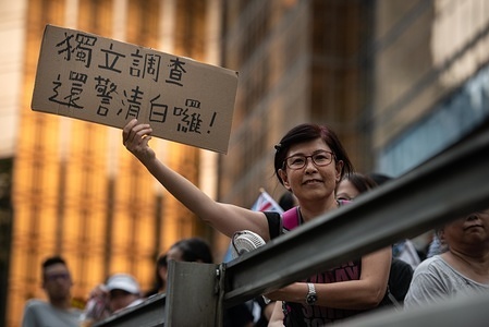 A woman shows a cardboard piece with a message against the extradition law to China during the protest.