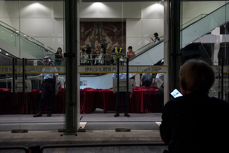 A protester waits outside the stadium as police stand guard inside glass doors during the demonstration.
Protesters gathered outside the Queen Elisabeth Stadium where Carrie Lam was scheduled to speak. Protesters chanted various slogans and heckled the police standing guard outside. Protesters continue to reaffirm the '5 Demands' as China's National Day inches closer.