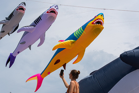 A tourist takes a photo of the giant shark kites on the Pattaya beach during the festival. The 2026 Beach Pattaya International Kite showcases more than 150 fancy giant kites from 12 countries around the world in Chonburi, Thailand.