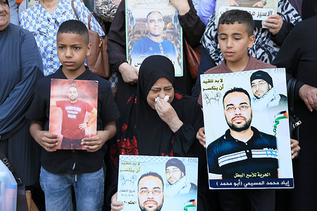 A Palestinian grandmother weeps as her grandchildren surround her, holding up posters of their fathers and brothers, Palestinian prisoners held in Israeli jails. The families reported that their sons are living in deplorable conditions, with severe shortages of food and water, denied access to showers, and completely isolated from the outside world. Released Palestinians have also reported widespread skin diseases among prisoners in Israeli detention centers.