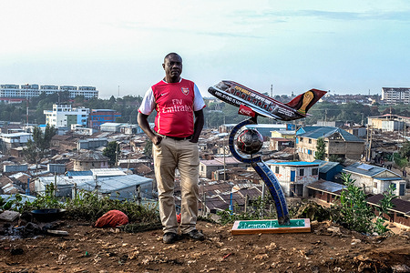 Bernard Oduor, a soccer fan and supporter of Arsenal F.C since 1998, takes a posture close by his World Cup trophy he created to be presented to H.E President Uhuru Kenyatta during the welcoming of the FIFA World Cup trophy tour in Nairobi. The FIFA World Cup trophy landed in Kenya for a two-day tour including public viewing ahead of this year's World Cup in Qatar.