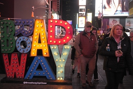 People walk past a Broadway sign in Times Square, Manhattan, New York City.