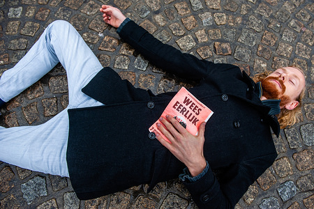 A climate activist lays on the ground while holding a placard during the performance.
Before the International Extinction Rebellion week starts in Amsterdam, a group of XR activists gathered in the center of the city to make a People’s Declaration of Climate Crisis. They also performed a 'die-in-action' which involves a group of people assembling at a place and dropping dead on the ground while dressed up thematically and holding adequate posters and banners.