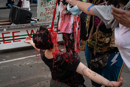 A protester on her knees gets doused in fake blood as they spread the message "blood on your hands" to the attendees of the expo during the rally. For the final day of Land Forces, a weapons expo, protesters dressed up as zombies and doused themselves in fake blood. They put children's shoes In front of police lines to represent the Palestinian children killed. During the demonstration, protesters were also blowing bubbles shouting at police "you've got no friends, we've got bubbles".