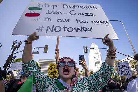 A protester chants slogans while holding a placard expressing her opinion during the demonstration. Protesters attend a demonstration calling for “No War on Iran,” “No War on Immigrants,” and “No War on Palestine” at Pershing Square in downtown Los Angeles.
