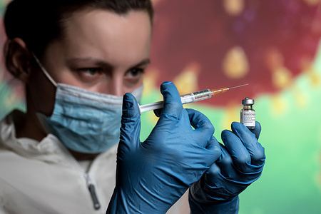 In this photo illustration a medical worker holding a syringe and a vial with Pfizer Covid-19 vaccine.