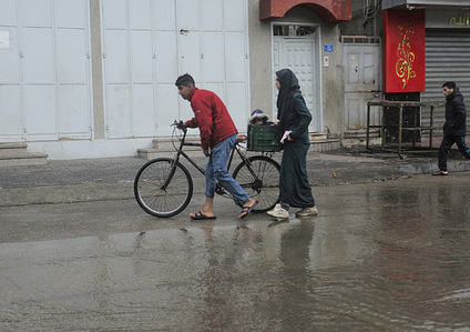 Palestinians walk along the street of Jabalia refugee camp, amid the heavy rain in the northern Gaza Strip.