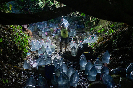 A man seen carrying a water container filled from the remaining flow of the Sumur Bendung spring on Mount Batur. A prolonged dry season has left residents in the hilly area facing a shortage of clean water for the past month, requiring them to walk about one kilometre through forest trails each day to collect water from the natural spring.