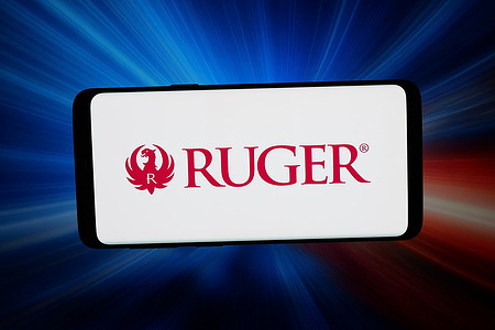 In this photo illustration, the US firearms business Sturm Ruger Company Inc. logo is seen displayed on a smartphone in front of abstract background on computer screen.