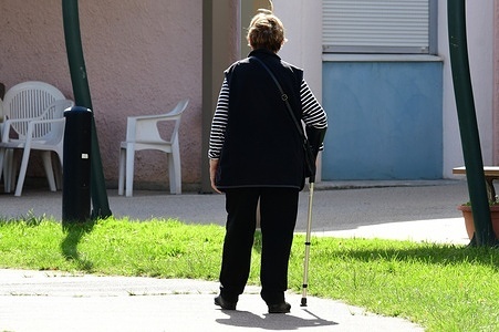 A woman with a cane seen in front of a residential facility for dependent elderly people in the town.