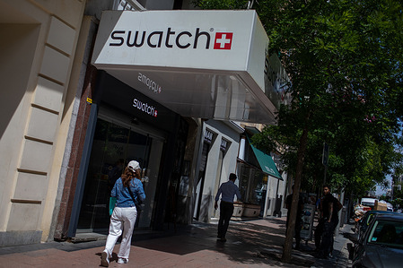 Pedestrians walk past the Swiss watchmaker Swatch store in the center of Madrid.