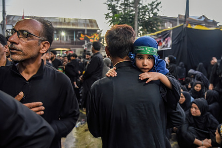 A Kashmiri Shia girl looks on from her father's shoulder during the Muharram procession in Srinagar.Muharram is the first month of Islam. It is one of the holiest months in the Islamic calendar. Shia Muslims commemorate Muharram as a month of mourning in remembrance of the Martyrdom Islamic Prophet Muhammad's grandson Imam Hussain, who was killed on Ashura (10th day of Muharram) in the battle of Karbala in 680 A.D.