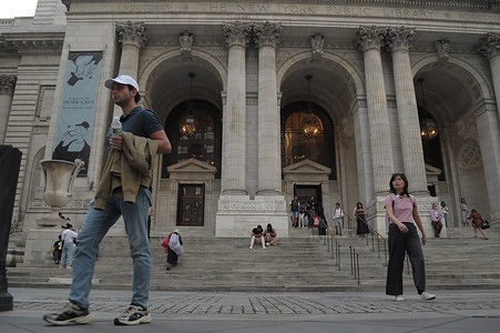 People walk down the stairs of the New York Public Library.