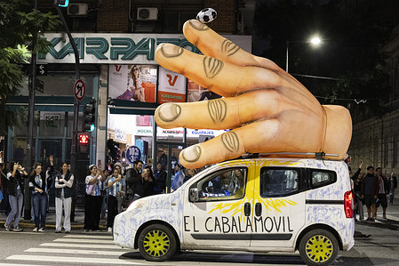 A car heading toward the Obelisk carries an inflatable "Hand of God" on its roof. Following the victory secured by Lionel Scaloni’s squad, thousands of fans poured into the streets to celebrate. While various spots across the city were packed, the heart of the gathering was at the Obelisk, as per tradition.