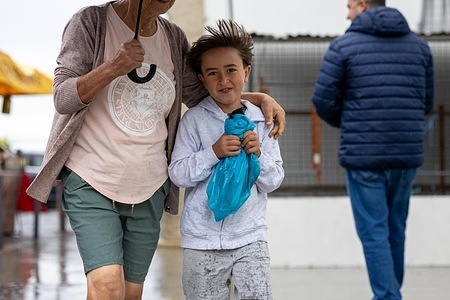 A boy seen doing the traditional laps around the church while holding the chicken followed closely by his grandmother during the Romaria. The Romaria is a traditional religious pilgrimage in São Bartolomeu do Mar, where participants take part in a Holy Bath as part of the annual celebration. The tradition attracts locals and visitors to the beach for the ritual