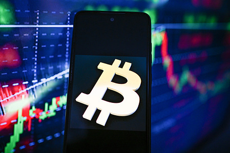 In this photo illustration, a Bitcoin logo is seen displayed on a smartphone with stock market percentages on the background.