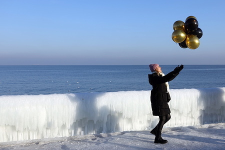 A woman poses with balloons on the frozen promenade of Langeron Beach. Odessa has been experiencing temperatures down to -10°C at night and strong gusts of wind for two weeks. As a result, seawater has effectively frozen.