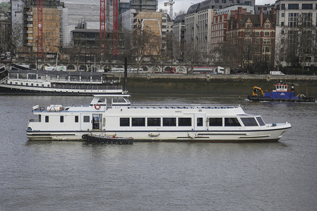 Various vessels, ferries and sightseeing boats are seen on the Thames River in London during a cloudy day.