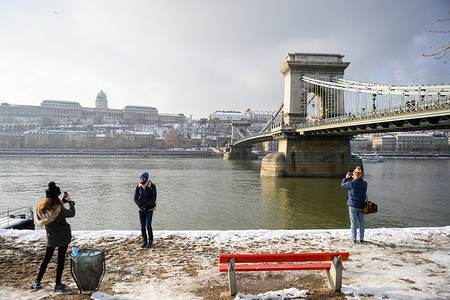 People are seen photographing themselves next to the Chain Bridge.