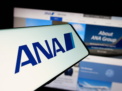 In this photo illustration, a smartphone with the logo of company All Nippon Airways Co. Ltd. (ANA) is seen on screen in front of website.