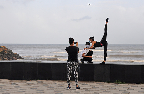 A woman takes support of a boy to perform a yoga pose as another woman takes pictures.
Every year, June 21 is recognized as International Yoga Day. Yoga embodies unity of mind and body, thought and action, a holistic approach that is valuable to our health and our well-being. Yoga is not just about exercise; it is a way to discover the sense of oneness with yourself, the world and nature.