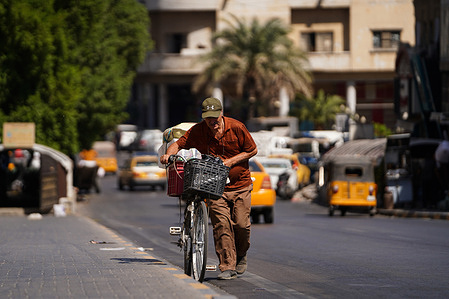 An Iraqi man pushes a bicycle on the Ahrar bridge across the Tigris river in central Baghdad.